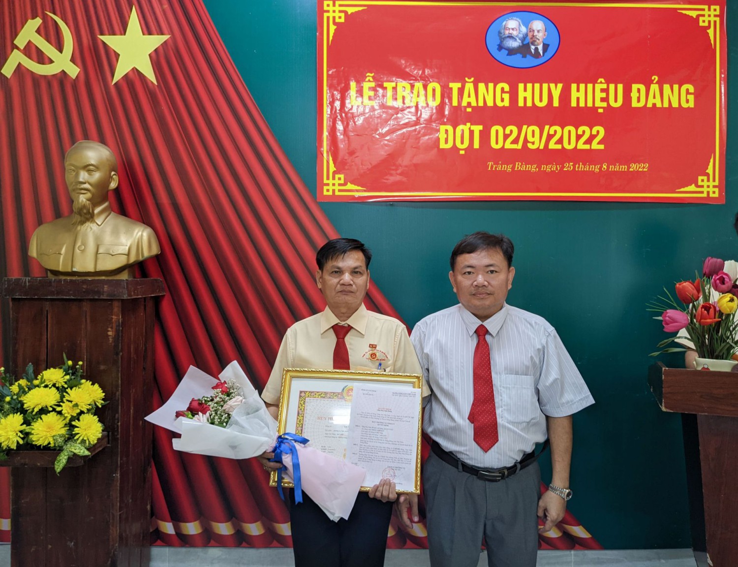 Ông Hà Minh Dảo- Ủy viên Ban Thường vụ Thị ủy, Phó Chủ tịch UBND thị xã trao Huy hiệu Đảng và tặng hoa chúc mừng đảng viên Thân Văn Quí.