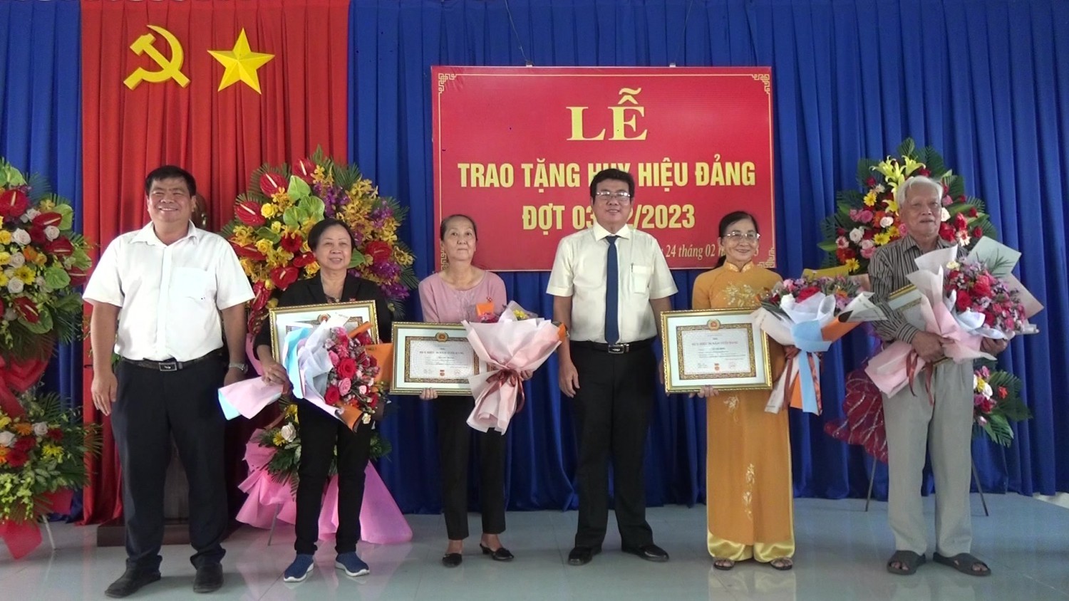 Ông Hồ Văn Hồng- Phó Bí thư Thường trực Thị ủy, Chủ tịch HĐND thị xã Trảng Bàng (thứ ba, từ phải qua) tặng hoa, trao Huy hiệu Đảng cho các đảng viên tại phường Trảng Bàng.
