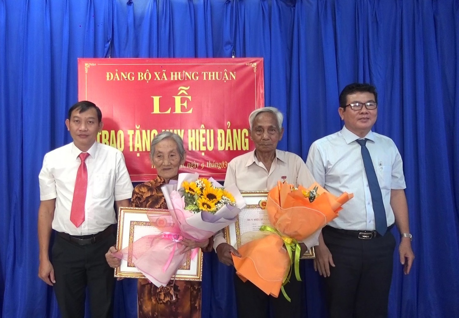 Ông Hồ Văn Hồng- Phó Bí thư Thường trực Thị ủy, Chủ tịch HĐND thị xã (bìa phải) tặng hoa, trao Huy hiệu Đảng cho các đảng viên tại xã Hưng Thuận